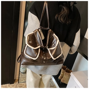 Detail of a brown PU leather shoulder bag with white shearling trim and silver metal studs