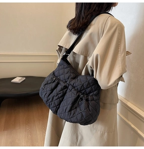Detail view of black quilted puffer shoulder bag with side drawstring adjusters