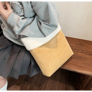 Detail of yellow faux suede crossbody bag with soft white faux fur trim on model