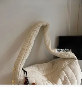 Close-up of a white quilted nylon tote bag with thick padded handles and zipper closure