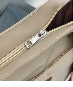 Close-up of smooth silver metal zipper and durable nylon fabric on beige shoulder bag
