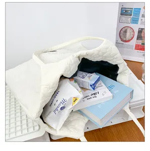 Spacious white tote bag featuring heart-shaped quilting and magnetic closure detail