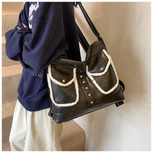 Detail of black PU leather shoulder bag with white faux fur trim and metal rivets