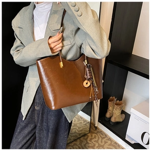 Détail du sac cabas en cuir PU marron avec texture vintage et breloque à glands