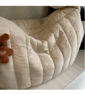 Close-up of beige quilted puffer bag featuring a cute brown plush bear charm and soft fabric
