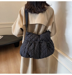 Detail of black quilted nylon shoulder bag with drawstring accents and wide strap