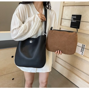Detail of black lychee grain leather saddle bag with silver logo and brown inner pouch