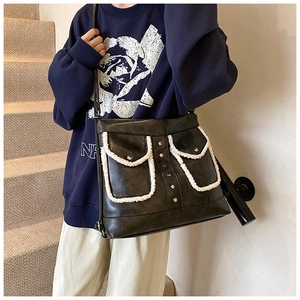 Detail of black PU leather shoulder bag with white fleece trim and decorative metal rivets