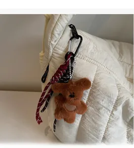 Close-up of brown plush bear charm with woven rope attached to a white quilted bag