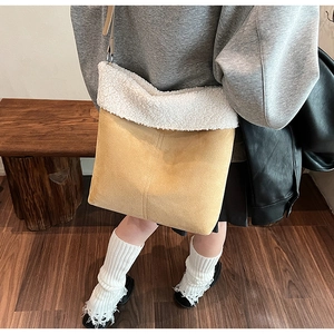 Detail view of camel suede shoulder bag featuring soft white faux shearling trim accents