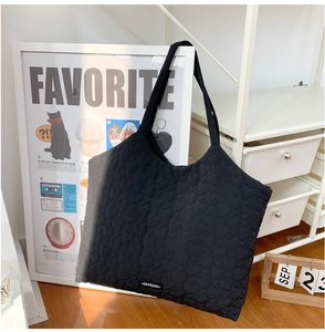 Close-up of black heart-quilted tote bag featuring soft fabric texture and logo label