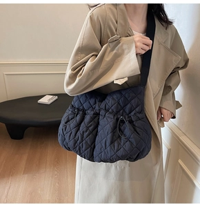 Close-up of black quilted nylon crossbody bag featuring drawstring sides and wide shoulder strap