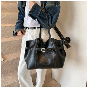 Dettaglio della borsa tote nera in pelle PU con texture vintage e fibbia a cintura decorativa