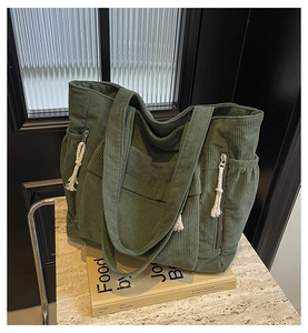 Détail du cabas en velours côtelé vert foncé avec fermeture éclair latérale et cordon blanc