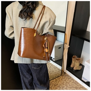 Détail du sac cabas en cuir PU marron brillant avec breloques et fermoir métallique