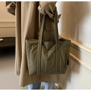 Detail of olive green nylon tote bag with parallel stitching and spacious shoulder straps
