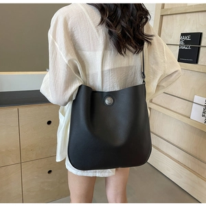 Detail of black pebbled leather tote bag with vintage silver metal buckle and wide strap