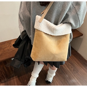 Detail of yellow suede bucket bag with soft white faux shearling trim and leather strap