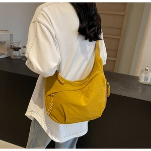 Detail of mustard yellow crescent bag with woven zipper pull on casual shoulder strap