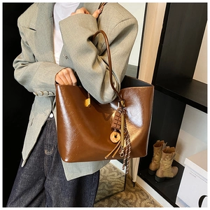 Détail d'un cabas en cuir marron brillant avec des breloques beignets et chocolatées