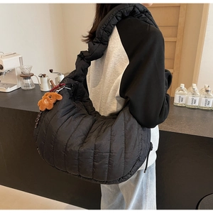 Detailed view of black quilted puffer hobo bag with a cute brown bear charm on strap