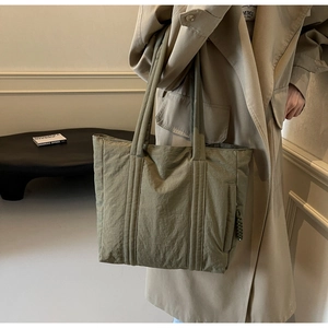 Detail of army green nylon tote bag showing pleated texture and craftsmanship on shoulder