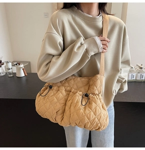 Detail of quilted mustard yellow shoulder bag featuring wide strap and drawstring closure