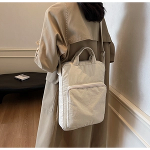 Rückansicht eines Modells mit einer beigefarbenen Nylon-Schultertasche mit Gurt