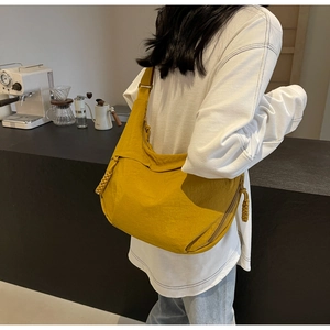 Detail view of yellow nylon crescent dumpling bag with decorative zipper on model