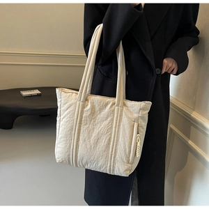 Detail view of the spacious beige pleated fabric tote bag with side zipper and woven rope