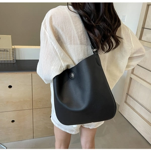 Detailed view of black litchi grain PU leather shoulder bag with round metal buckle decor