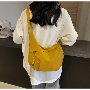 Close-up of mustard yellow dumpling crossbody bag with adjustable wide strap and woven zip puller