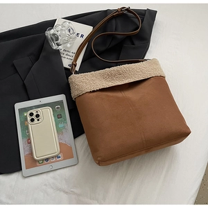 Detail of suede shoulder bag featuring plush faux shearling trim and stitching