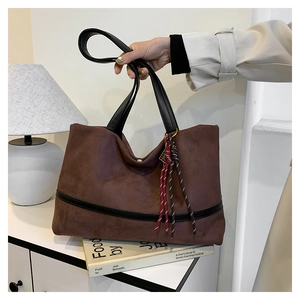 Détail d'un sac cabas marron en daim avec garnitures en cuir noir et cordon décoratif