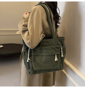 Vue détaillée du sac fourre-tout en velours côtelé vert foncé avec des glands