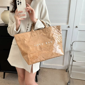 Mirror selfie showing the large brown Tyvek tote bag with white TOTE BAG print
