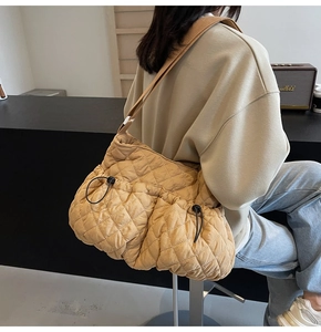 Chic quilted cloud bag in mustard yellow worn as a crossbody bag for stylish women