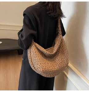 Vue détaillée du grand sac hobo à imprimé léopard porté sur un manteau noir élégant