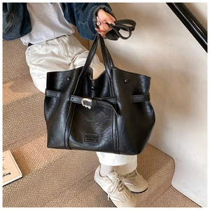 Dettaglio della borsa tote in ecopelle nera con fibbia argentata e cinturino decorativo