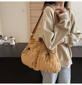 Close-up of ginger yellow quilted shoulder bag featuring two front drawstring pockets