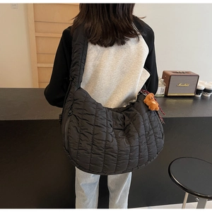 Detail of black quilted shoulder bag with a cute brown bear charm on the side