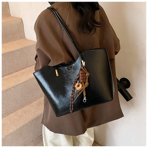 Détail d'un grand sac cabas en similicuir noir brillant avec des breloques fantaisie