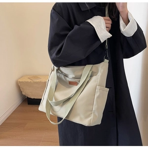 Beige canvas tote bag featuring adjustable shoulder strap and multiple side pockets