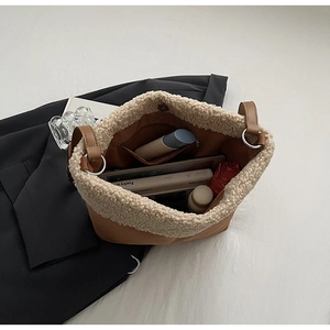 Detail view of large brown fuzzy tote bag with cream fleece trim and interior zip pocket