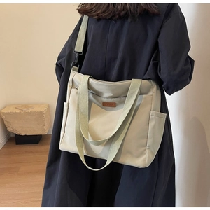 Detail view of khaki canvas tote with adjustable strap and side pocket on a model