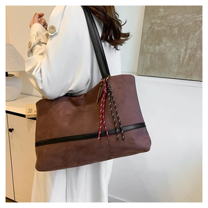 Détail d'un grand sac cabas en velours avec lanières en cuir et pompon tissé décoratif