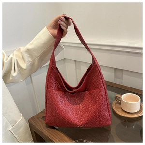Detail view of a woven red PU leather hobo shoulder bag held by a person in a home setting