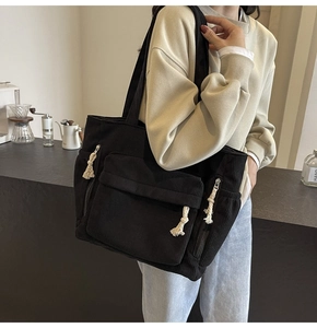 Vue détaillée du sac cabas en velours côtelé noir avec poche avant et nœuds décoratifs