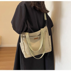 Detail of minimalist khaki canvas tote with adjustable strap and leather patch for daily use