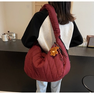 Detailed view of burgundy quilted shoulder bag with plush bear charm in daily use